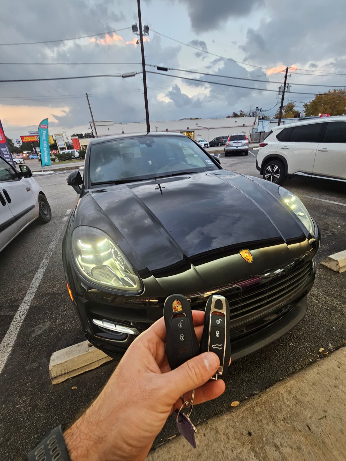 Porsche Cayenne key replacement at parking lot , two Porsche smart key fobs in hand, Houston TX