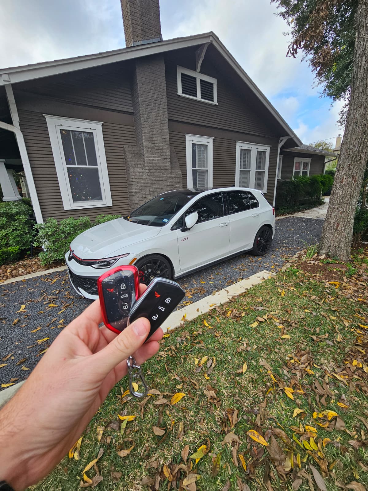 Volkswagen Golf GTI key replacement at residential driveway , two VW smart key fobs held in hand, Houston TX